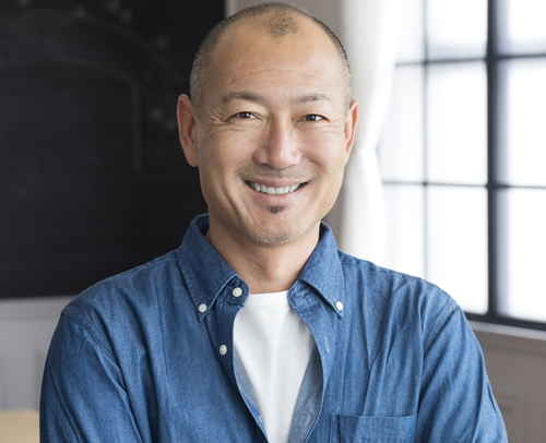 An Asian man in an office smiling at the camera