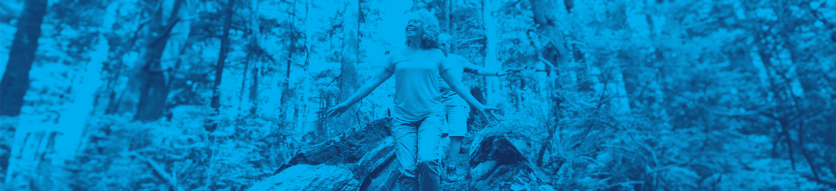 Older woman walking among tall trees